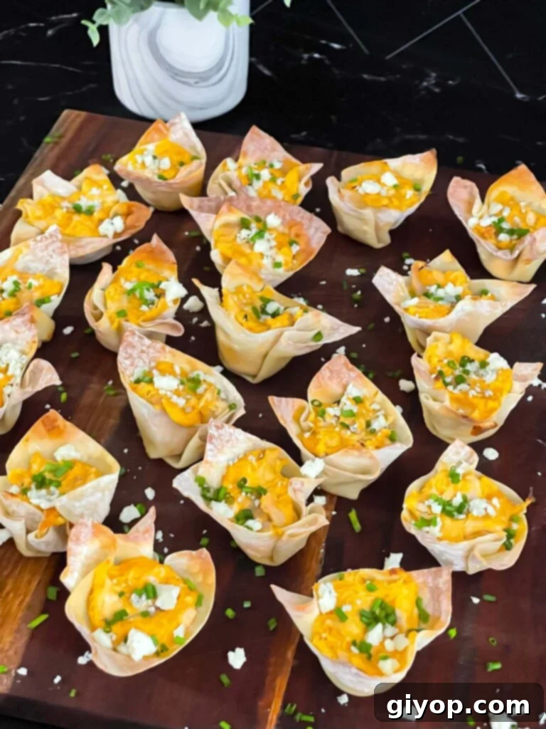 Buffalo chicken wontons garnished with chives and blue cheese crumbles on a cutting board, ready to eat.