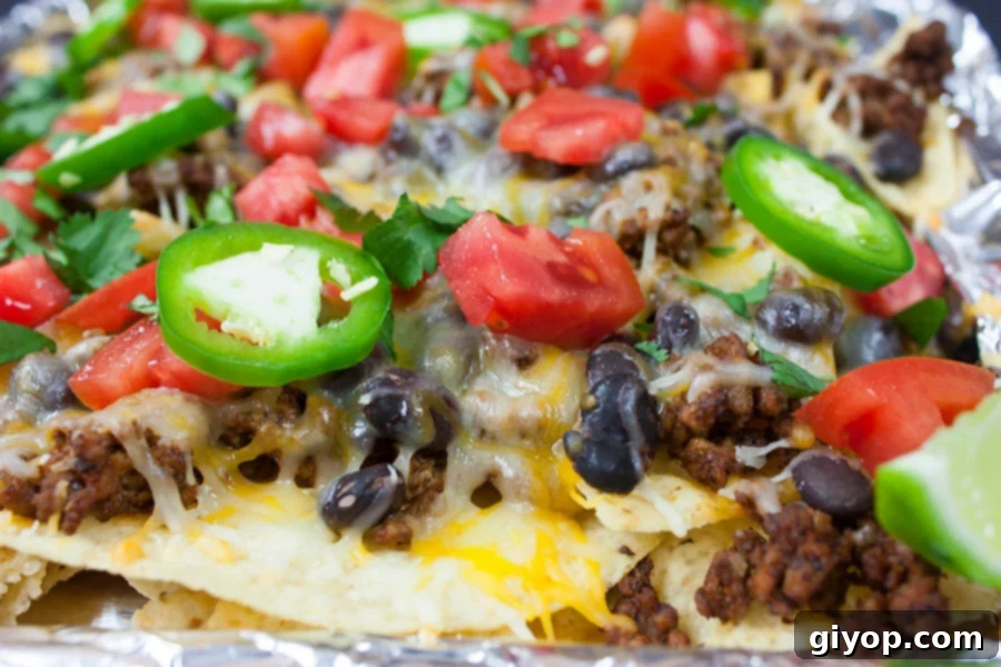 Loaded Sheet Pan Beef Nachos 3 Close-up of golden melted cheese and seasoned beef on nachos in a baking pan.