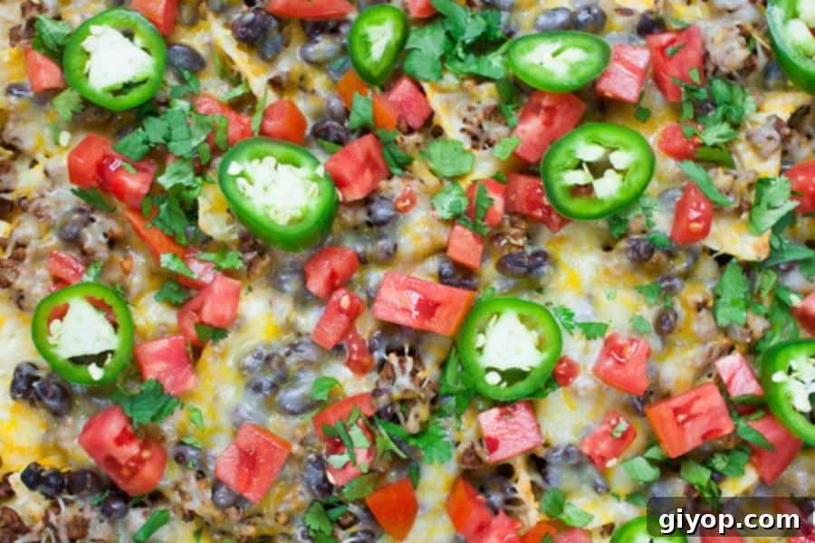 Loaded Sheet Pan Beef Nachos 7 A large serving of Sheet Pan Beef Nachos, beautifully arranged with various fresh toppings, ready to be enjoyed.