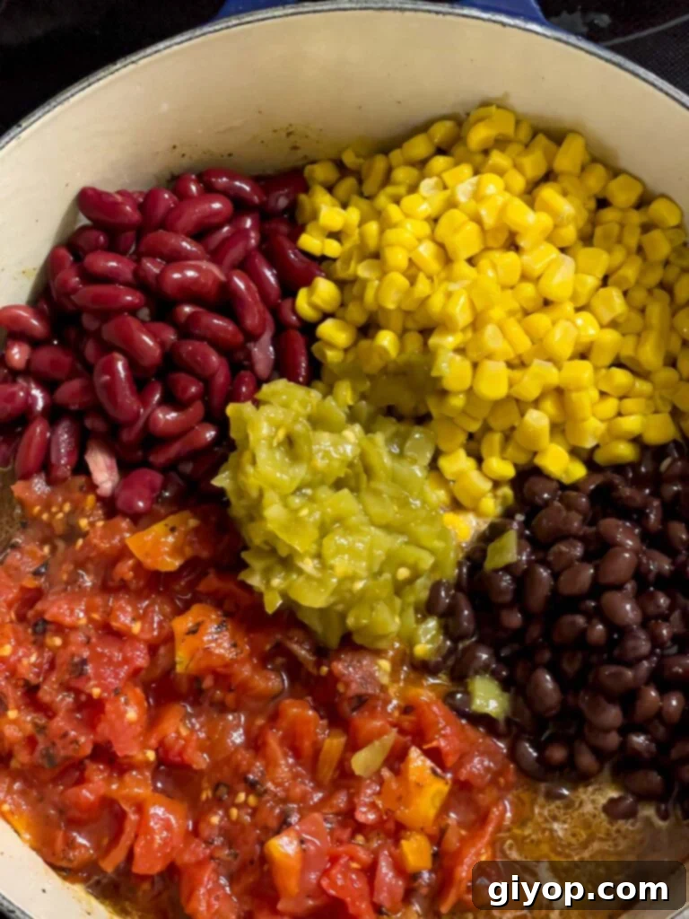 A variety of ingredients including beans, corn, and tomatoes added to the dutch oven.