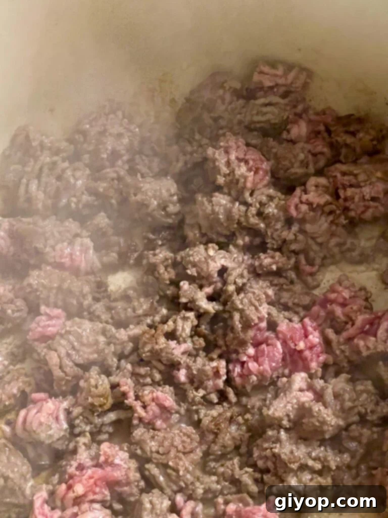 Ground beef cooking and browning in a dutch oven.