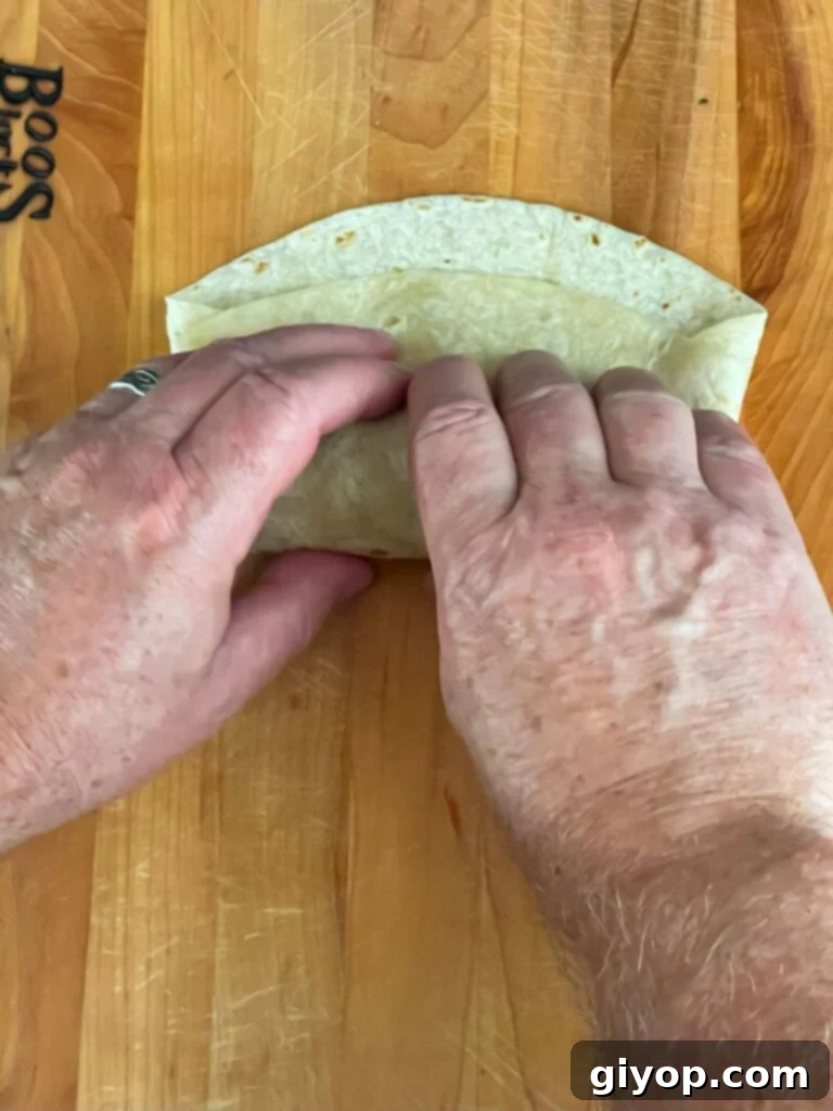 Wrapping the tortilla on a wooden board.