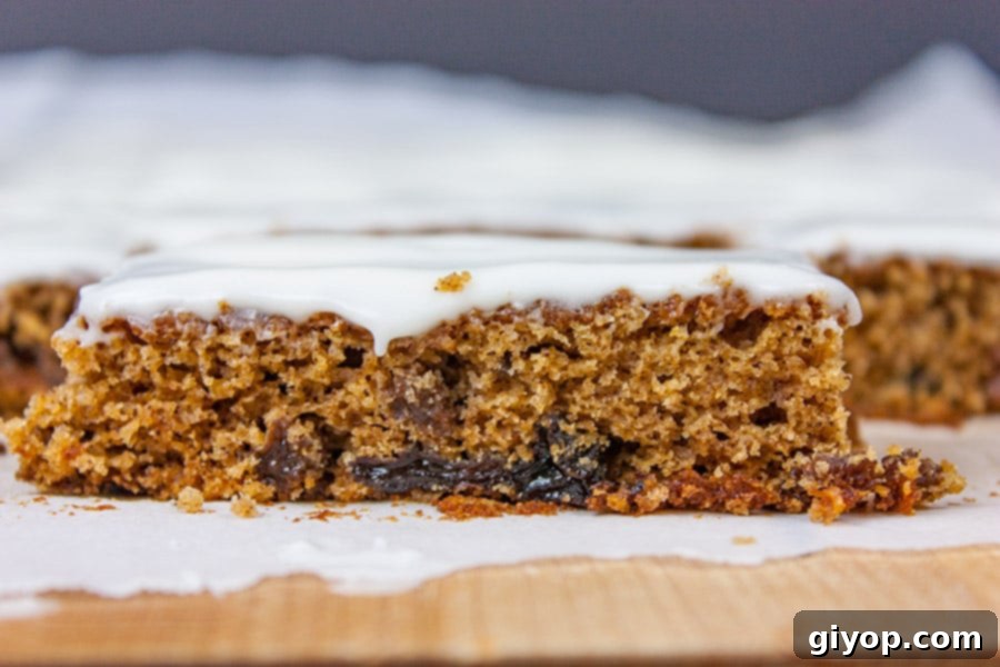 Cut raisin bars on a wooden cutting board, showcasing their moist texture and creamy frosting.