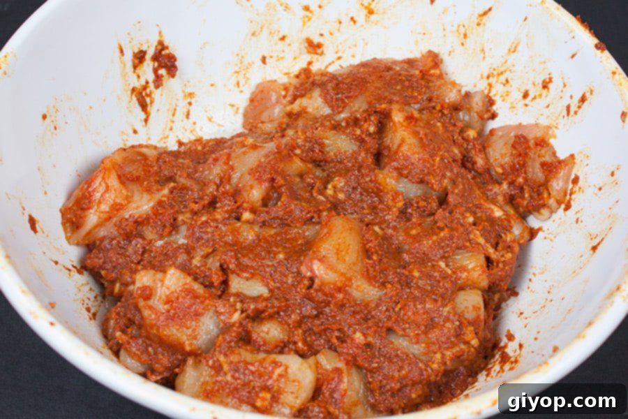 Smoky Bacon Glazed Chicken Kebabs 5 Chicken pieces thoroughly coated in bacon paste, marinating in a white bowl.