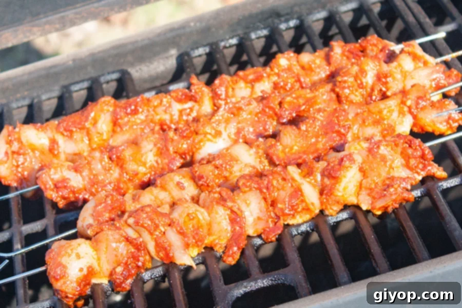 Smoky Bacon Glazed Chicken Kebabs 6 Bacon Paste BBQ Chicken Kebabs cooking on a hot grill, showing smoky charring.