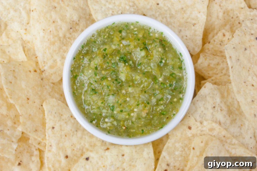 Homemade Roasted Tomatillo Salsa (salsa verde) served in a white ramekin, surrounded by crisp tortilla chips, ready for dipping.