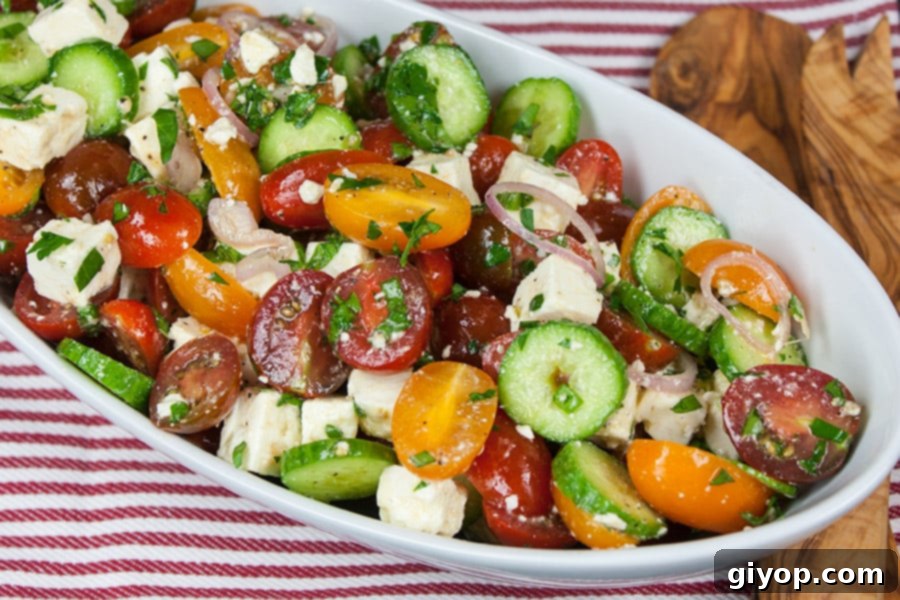 Fresh Feta Medley 8 Tomato Cucumber Feta Salad in a white serving bowl on a red striped tablecloth.