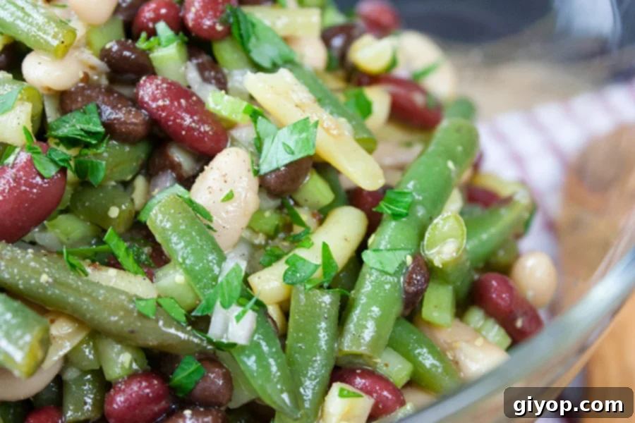 Homemade Five Bean Salad in a glass serving bowl, garnished with fresh parsley.