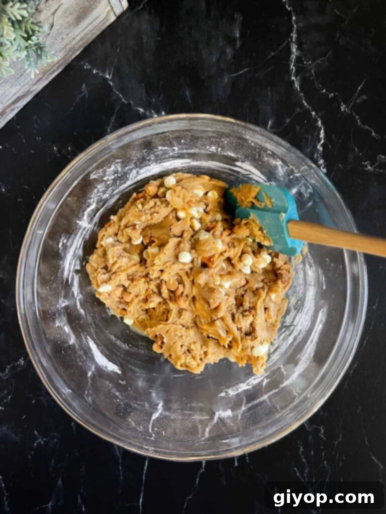Salted Butterscotch Pretzel Cookie dough in a glass bowl on a dark surface.