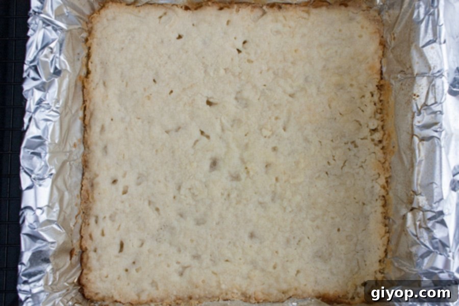Lemony Shortbread Cheesecake Bars 3 Lemon Cheesecake Shortbread Bars - baked shortbread crust in foil lined pan, showing the golden-brown edges.