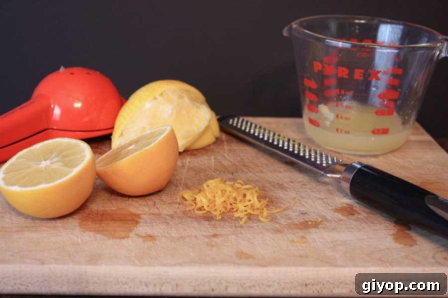 Fresh Meyer lemons and grated zest on a wooden board, highlighting their unique color and aromatic peel.