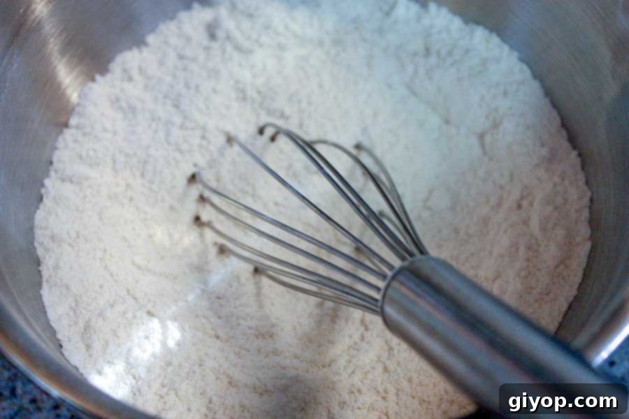 Dry ingredients, including flour, baking powder, and salt, combined in a metal bowl, ready for mixing.