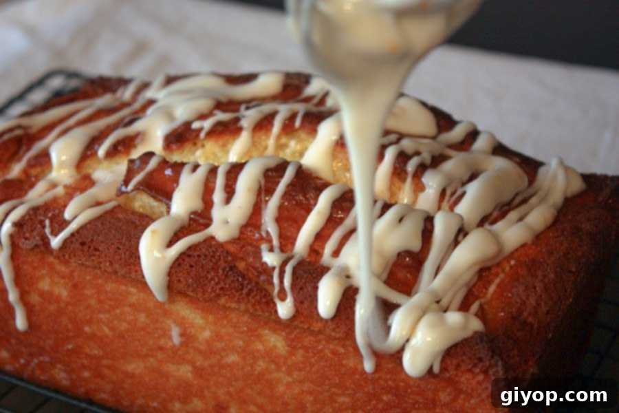 Icing being drizzled over the warm Meyer Lemon Loaf, creating a beautiful and delicious finish.