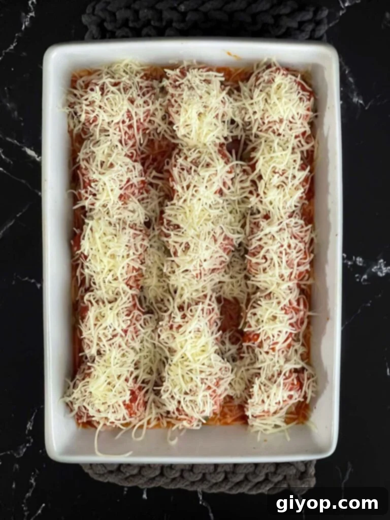Marinara sauce and shredded Italian blend cheese over the top of the meatballs in a light casserole dish.
