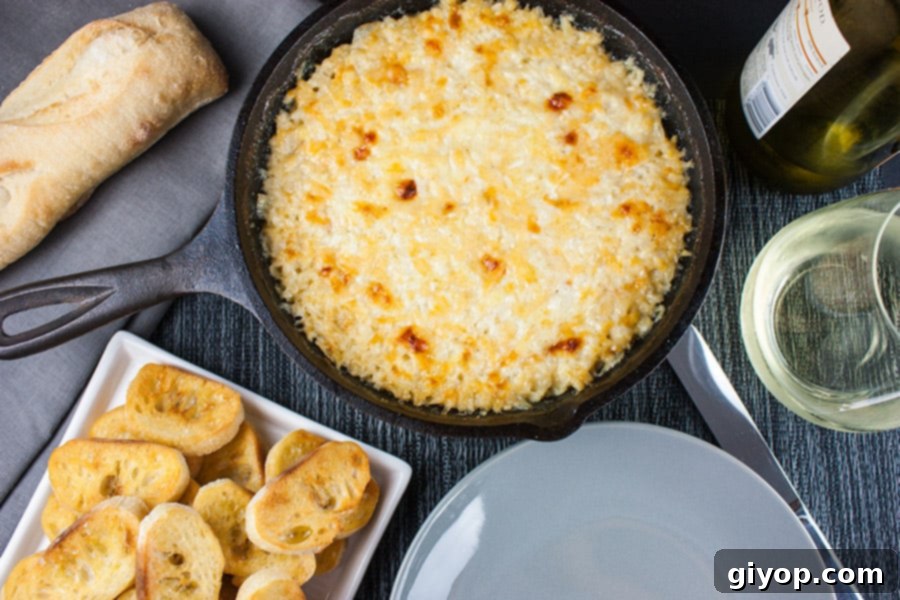 Baked Vidalia Onion Dip in a cast iron skillet, served with toasted baguette slices on a white serving platter.