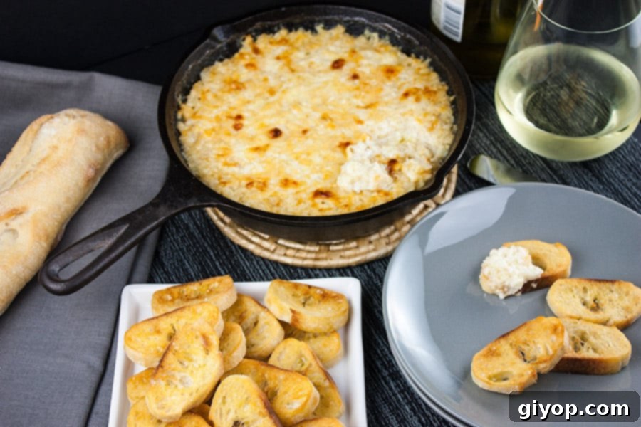 Baked Vidalia Onion Dip in a cast iron skillet on a gray plate, with toasted baguette slices.
