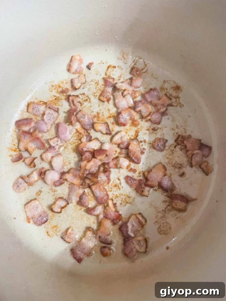 Chopped bacon frying in a dutch oven for southern green beans and potatoes recipe.