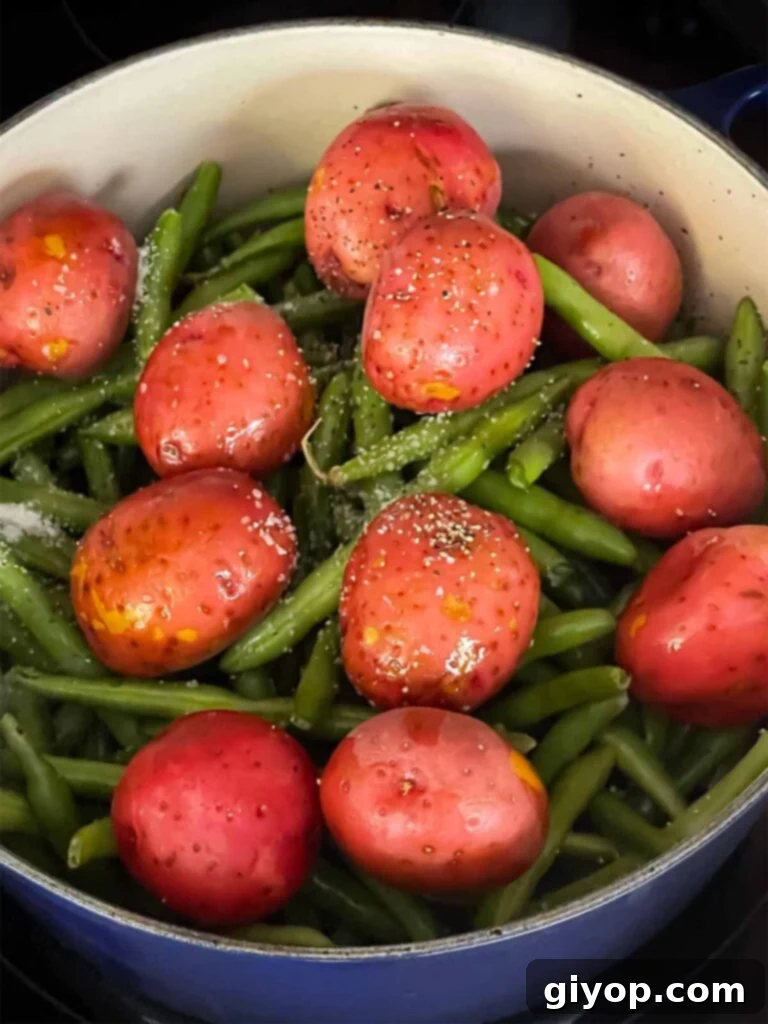 Green beans, baby potatoes, kosher salt and black pepper added to the dutch oven.