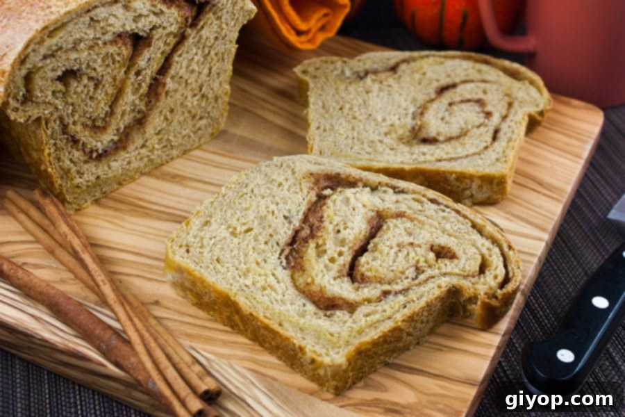 A close-up view of sliced Pumpkin Cinnamon Swirl Bread on a wooden cutting board, highlighting its appealing texture and swirl.