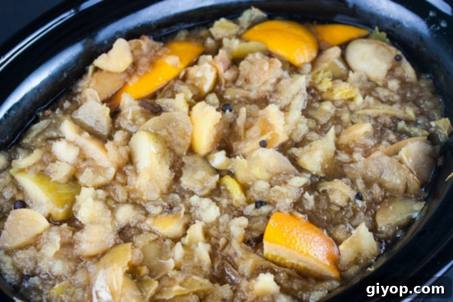 Ingredients for apple cider cooked in the crock of a slow cooker.