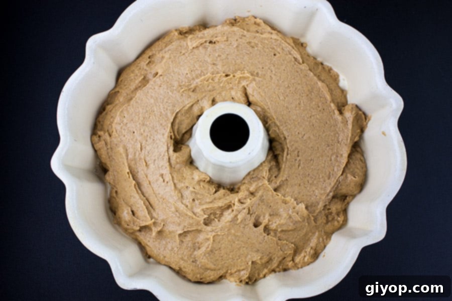 Smooth, orange-hued cake batter filling a fluted bundt pan.